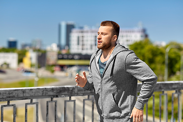 Image showing happy young man running across city bridge