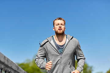 Image showing happy young man running across city bridge