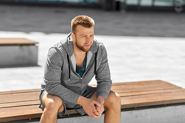 Image showing young man sitting on bench outdoors