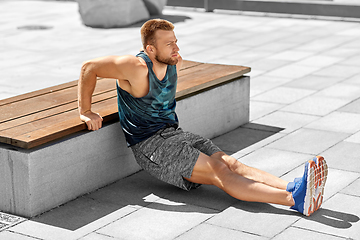 Image showing young man doing triceps dip on city street