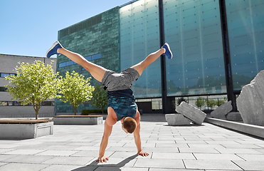 Image showing young man exercising and doing handstand outdoors