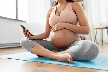 Image showing happy pregnant woman with phone doing yoga at home