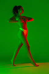 Image showing Beautiful female body on green background in neon light. Beauty, cosmetics, spa, depilation, diet and treatment, fitness concept.