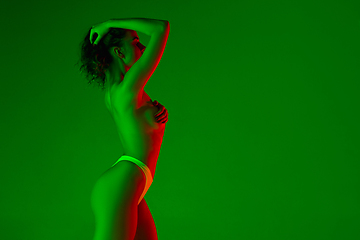 Image showing Beautiful female body on green background in neon light. Beauty, cosmetics, spa, depilation, diet and treatment, fitness concept.