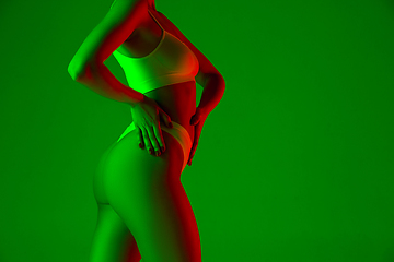 Image showing Beautiful female body on green background in neon light. Beauty, cosmetics, spa, depilation, diet and treatment, fitness concept.
