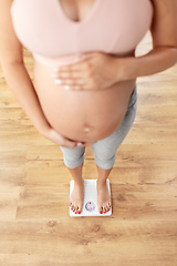 Image showing pregnant woman standing on scales at home