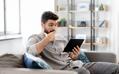 Image showing shocked man with tablet computer at home