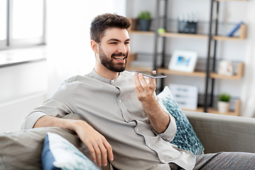 Image showing happy man with smartphone recording voice at home
