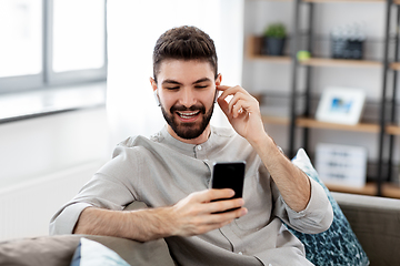 Image showing man in earphones listening to music on smartphone