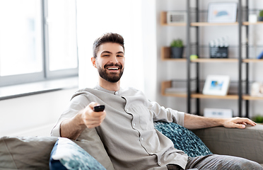 Image showing happy man with remote control watching tv at home