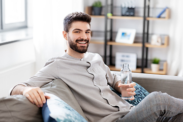 Image showing happy man drinking water from glass bottle at home