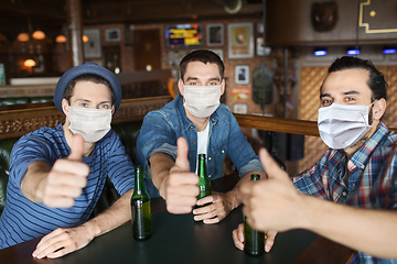 Image showing male friends in masks drinking beer at bar or pub