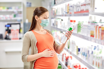 Image showing pregnant woman in mask choosing lotion at pharmacy