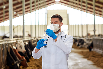 Image showing veterinarian in mask with syringe and cows on farm