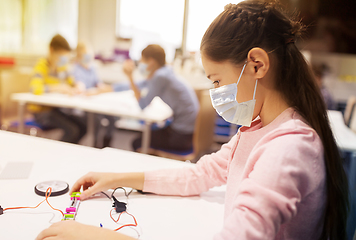 Image showing girl in mask building robot at robotics school