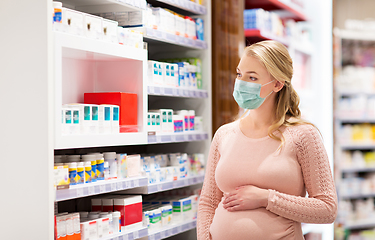 Image showing pregnant woman in mask with medicines at pharmacy