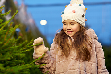 Image showing little girl choosing christmas tree at market