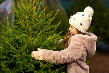 Image showing little girl choosing christmas tree at market