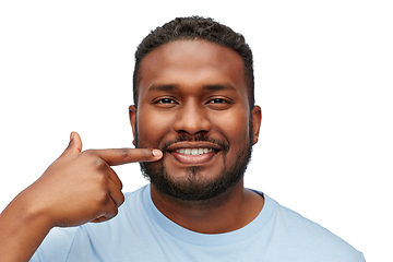 Image showing smiling man pointing finger to his mouth or teeth