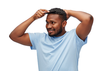 Image showing happy african american man brushing hair with comb