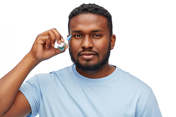 Image showing young african american man using eye drops