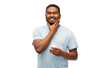 Image showing happy african man applying cream to his face