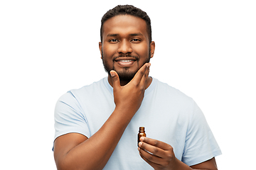 Image showing african man applying grooming oil to beard