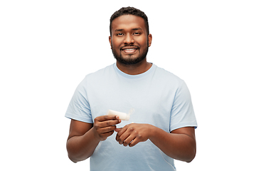 Image showing happy african man applying moisturizer to his hand