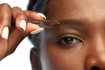 Image showing african woman with tweezers tweezing her eyebrow