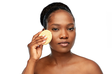 Image showing young woman cleaning face with exfoliating sponge