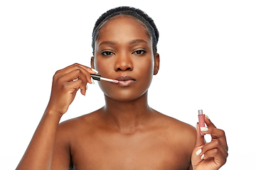 Image showing african american woman applying lip gloss