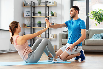 Image showing woman with personal trainer doing sit ups at home