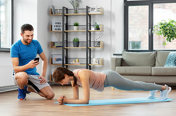 Image showing woman with personal trainer doing plank at home