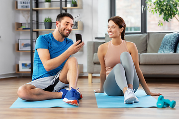 Image showing happy couple with smartphone doing sports at home