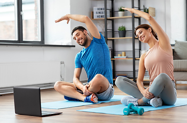 Image showing happy couple with laptop exercising at home