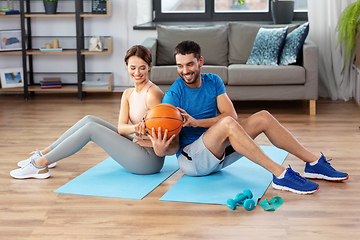 Image showing happy couple exercising with ball at home