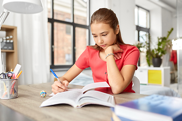 Image showing student girl with book writing to notebook at home