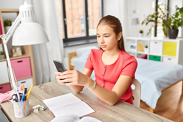 Image showing girl with smartphone distracting from homework