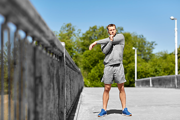 Image showing man stretching hand and shoulder on bridge