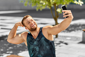 Image showing man taking selfie with phone and showing bicep