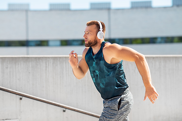 Image showing young man in headphones running upstairs outdoors