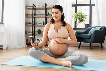 Image showing happy pregnant woman sitting on yoga mat at home