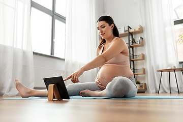 Image showing pregnant woman with tablet pc doing sports at home