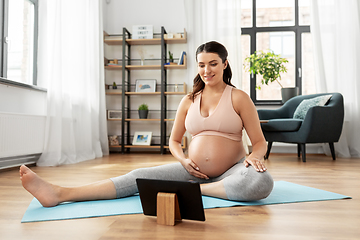 Image showing pregnant woman with tablet pc doing sports at home