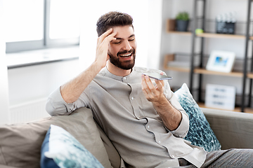 Image showing happy man with smartphone recording voice at home