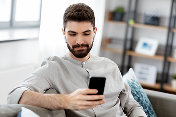 Image showing man in earphones listening to music on smartphone