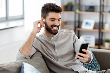 Image showing man in earphones listening to music on smartphone