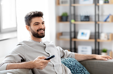 Image showing happy man with remote control watching tv at home