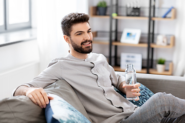 Image showing happy man drinking water from glass bottle at home