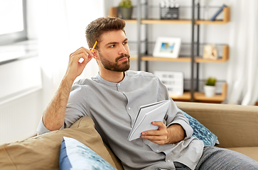 Image showing man writing to notebook and thinking at home